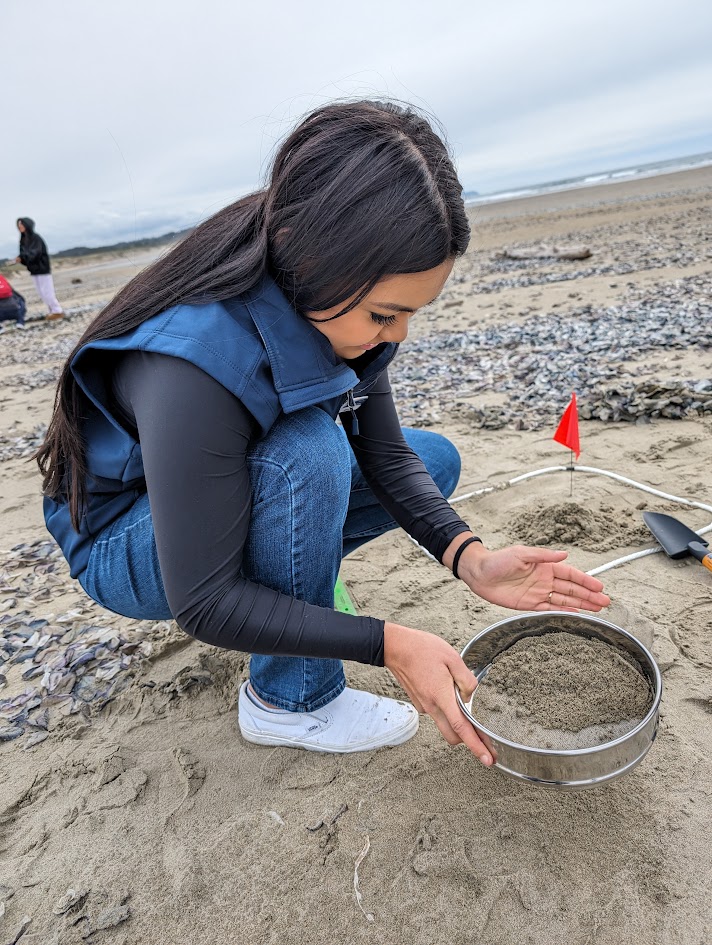 Bilingual Youth Program participant sifts through sand to find and collect microplastics