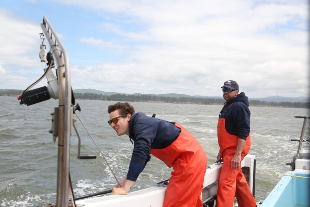 Batson (left) and Burke look over the side of the Gracie Lynn, checking for buoy movement