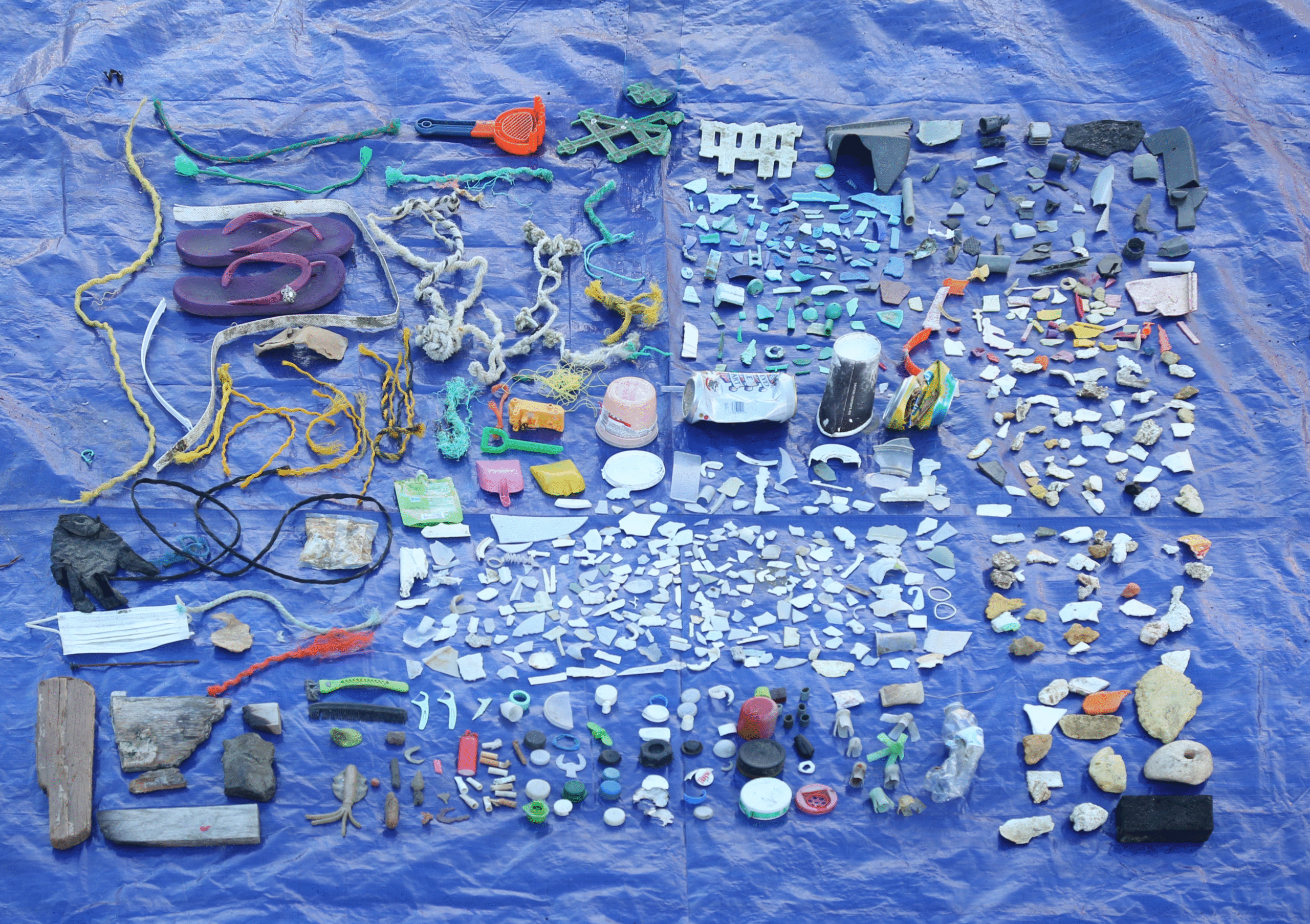 An arrangement of plastic beach debris is spread atop a tarp